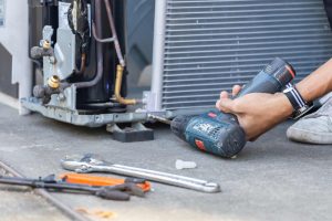 A worker replacing parts on an air conditioning unit