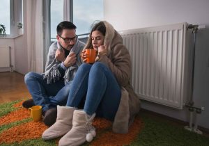 A couple draped in blankets and drinking hot beverages