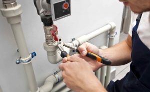 A worker with pliers diagnosing a boiler system