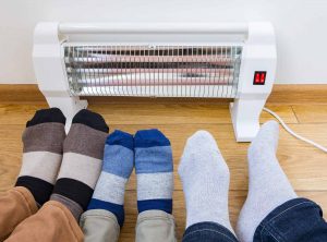 Parents and children warming their feet near a space heater