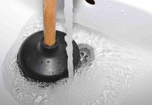 A plunger in a sink with running water