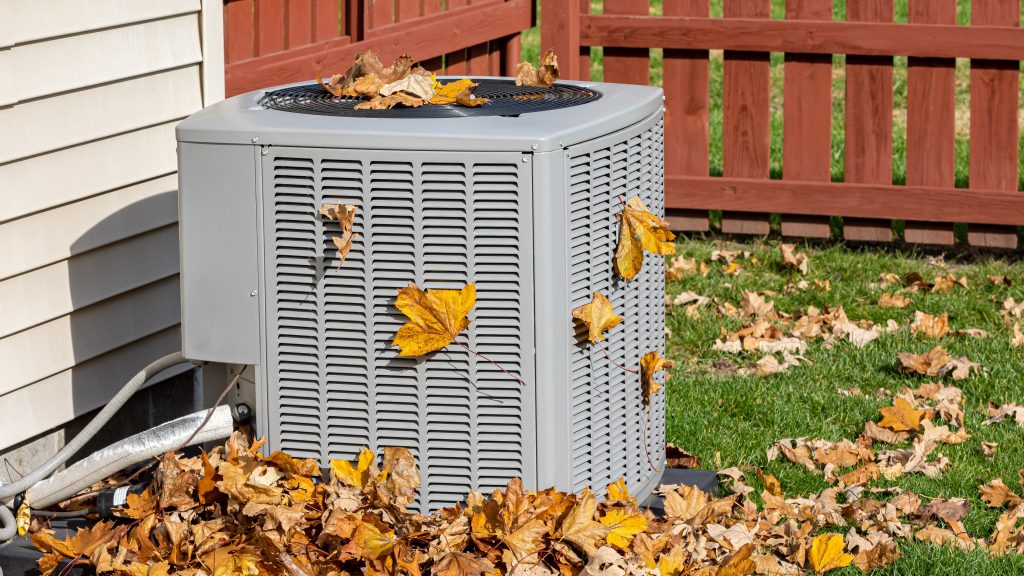 air conditioning and heating unit for house surrounded by fallen leaves